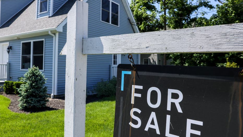 A "for sale" sign in front of house.